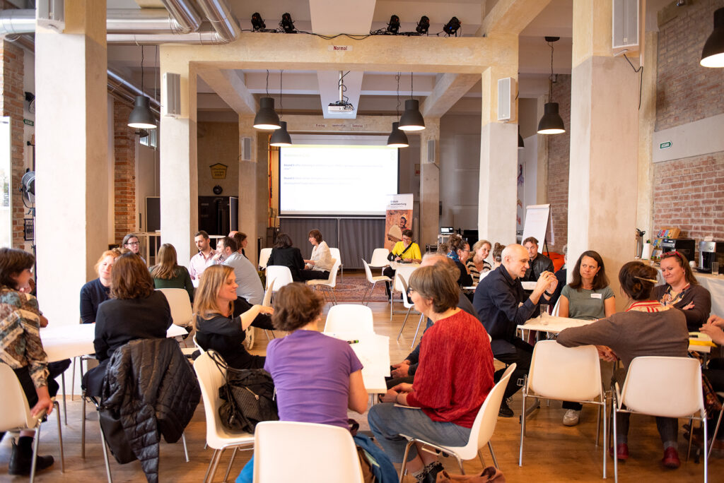 The participants gathered around tables in smaller groups for a World Café session.