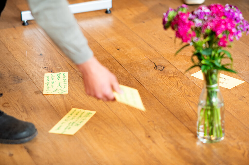 A participant puts a note on the floor next to a bouquet of flowers.