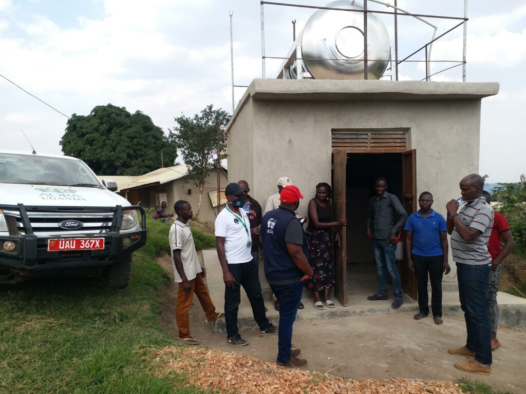 Menschengruppe vor Wasserkiosk im Rwamwanja Refugee Settlement in Uganda 