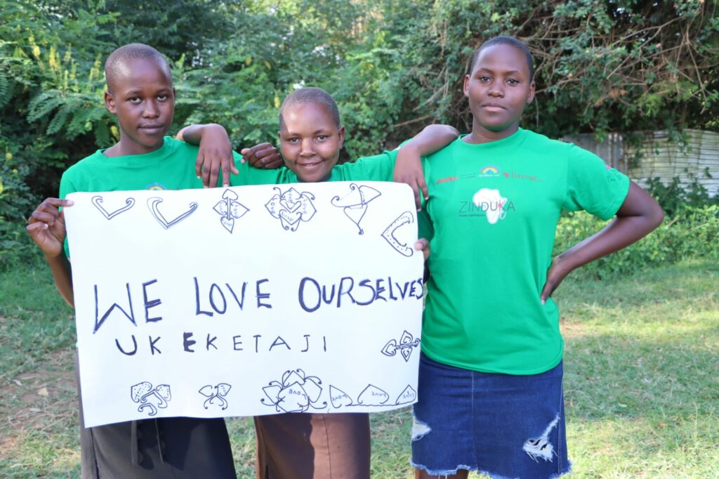 Drei Mädchen halten ein Schild mit Aufschrift "We love ourselves"