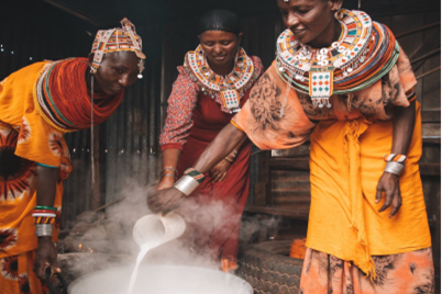 Bilaterale Klimaprojekte: Frauen in der kenianischen Projektregion stehen um einen vollen Topf und schütten Kamelmilch hinein.