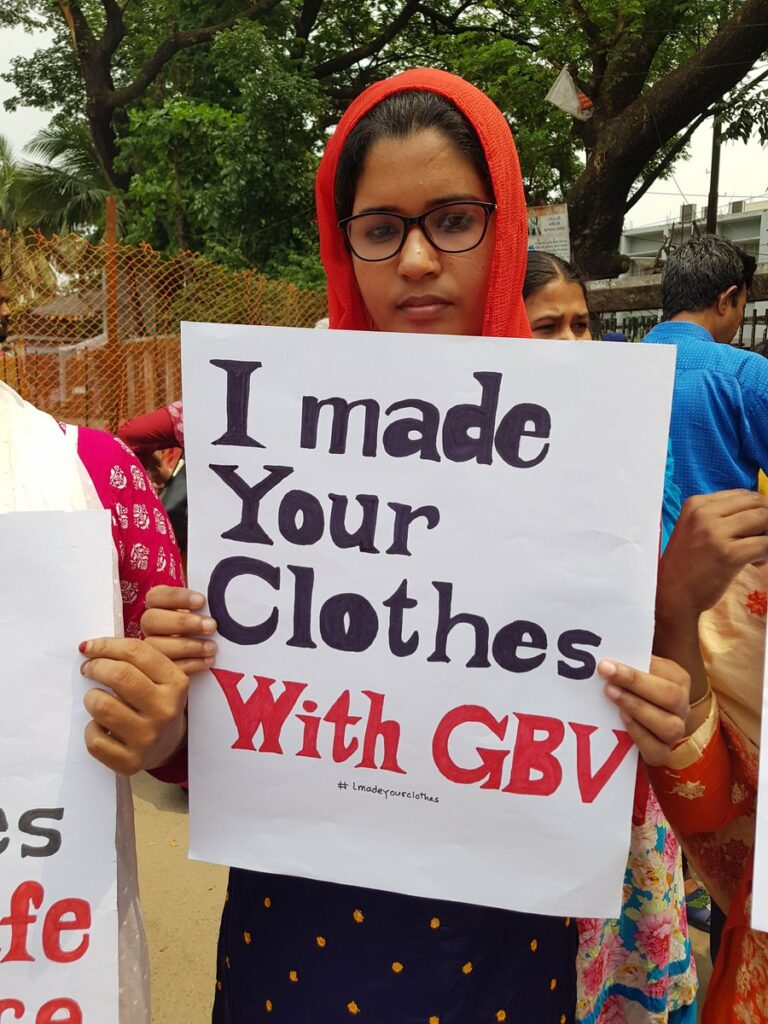 Frau mit Schild "I made your clothes with GBV"