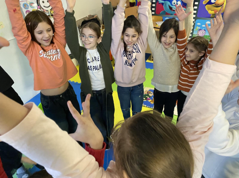 Kinder stehen im Kreis und recken ihre Hände in die Luft