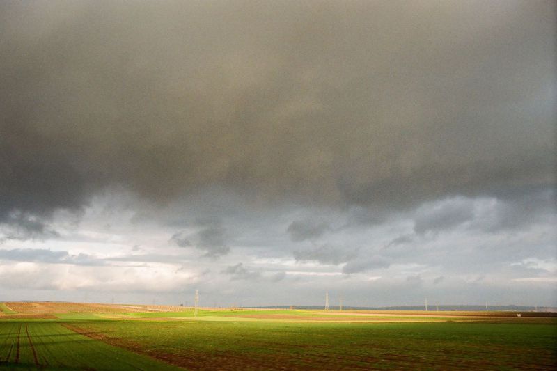 Dunkle Wolken über Feldern im niederösterreichischen Weinviertel, im Hintergrund Windräder